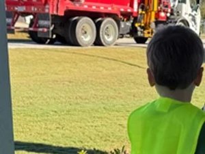 Toddler in safety vest waiting on porch for Friday morning garbage truck